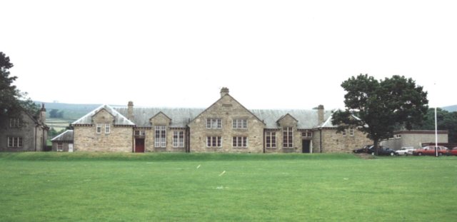A large stone building with a lawn

Description automatically generated