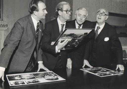 A group of men looking at a book

Description automatically generated with low confidence