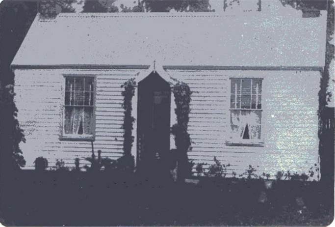 A white house with a door and windows
Description automatically generated
