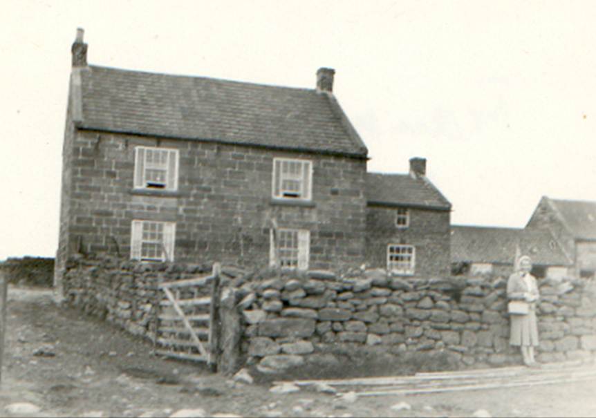 A couple of people standing in front of a stone house

Description automatically generated