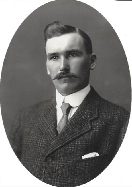 A vintage photo of a person in a suit and tie

Description automatically generated