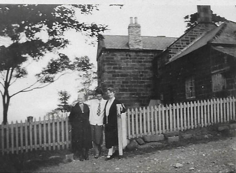 A black and white photo of a person walking by a fence
Description automatically generated