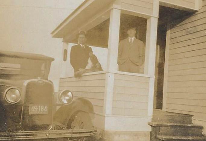 A couple of men standing in a porch
Description automatically generated