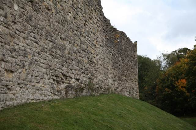 A stone wall with grass on the side
Description automatically generated