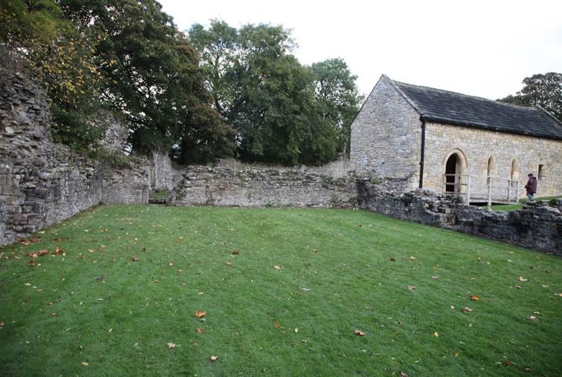 A stone building with a green lawn
Description automatically generated