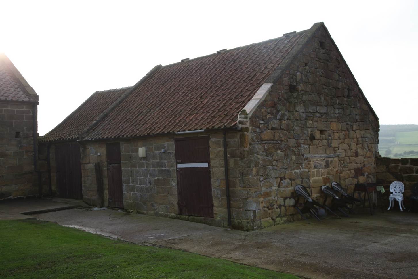 A stone building with a red roof
Description automatically generated