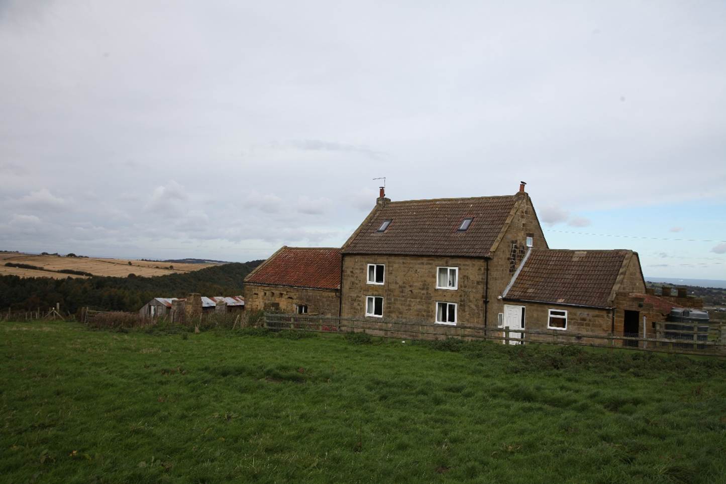 A stone house with a grassy field
Description automatically generated