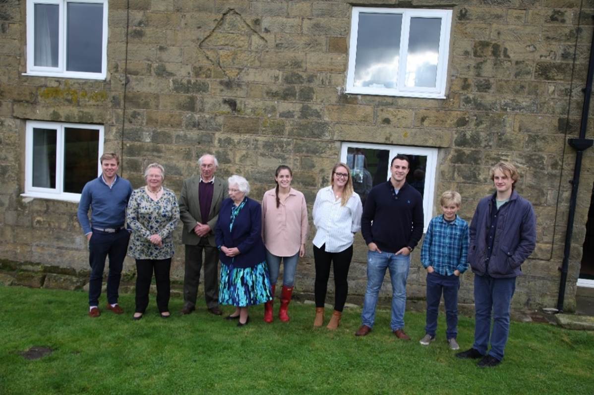 A group of people standing in front of a stone building
Description automatically generated