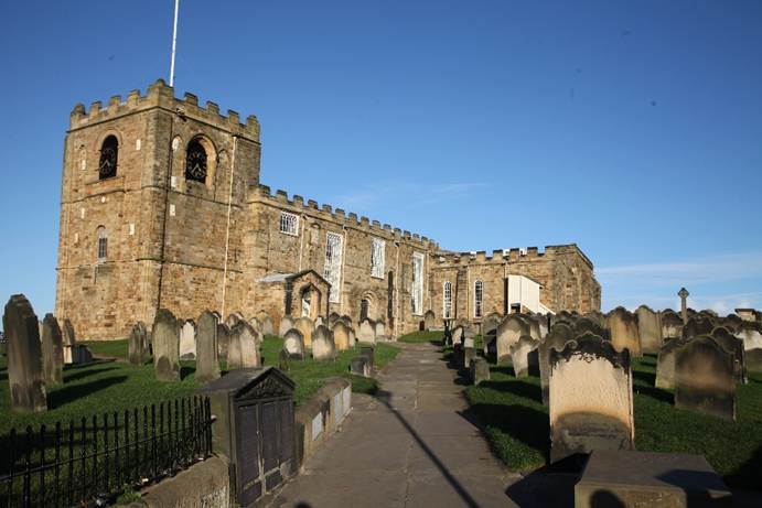 A stone building with a cemetery
Description automatically generated