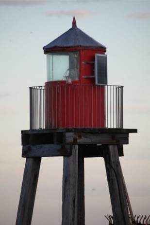 A red lighthouse on a pier
Description automatically generated